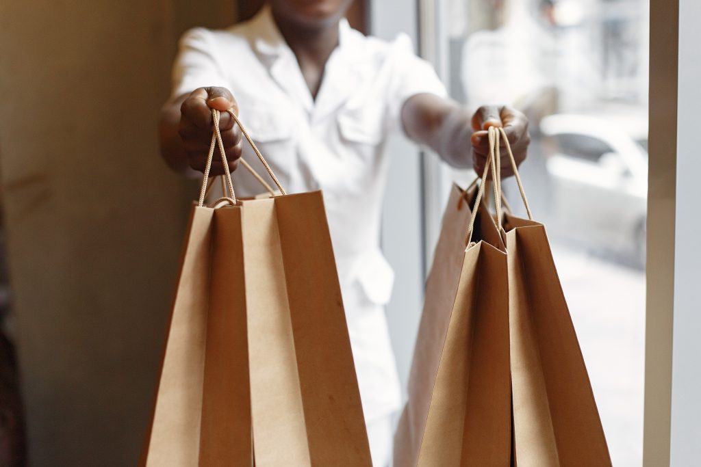 Black man in a cafe. Guy with shopping bags. Man in a white shirt.