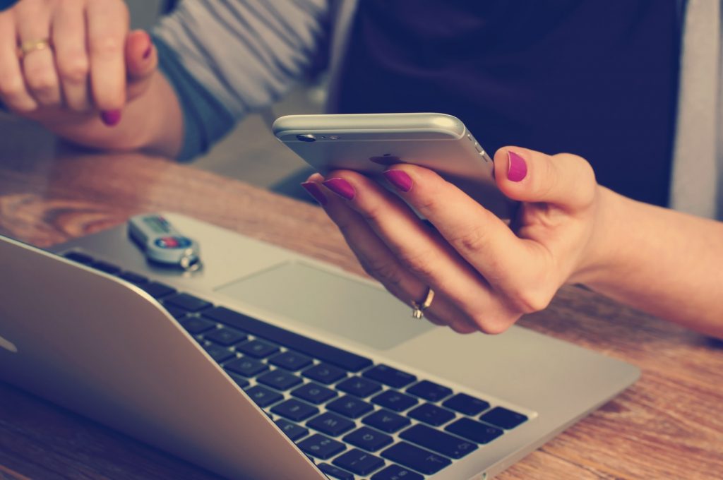 person sat at laptop with phone in hand too.