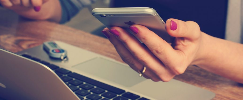 person sat at laptop with phone in hand too.