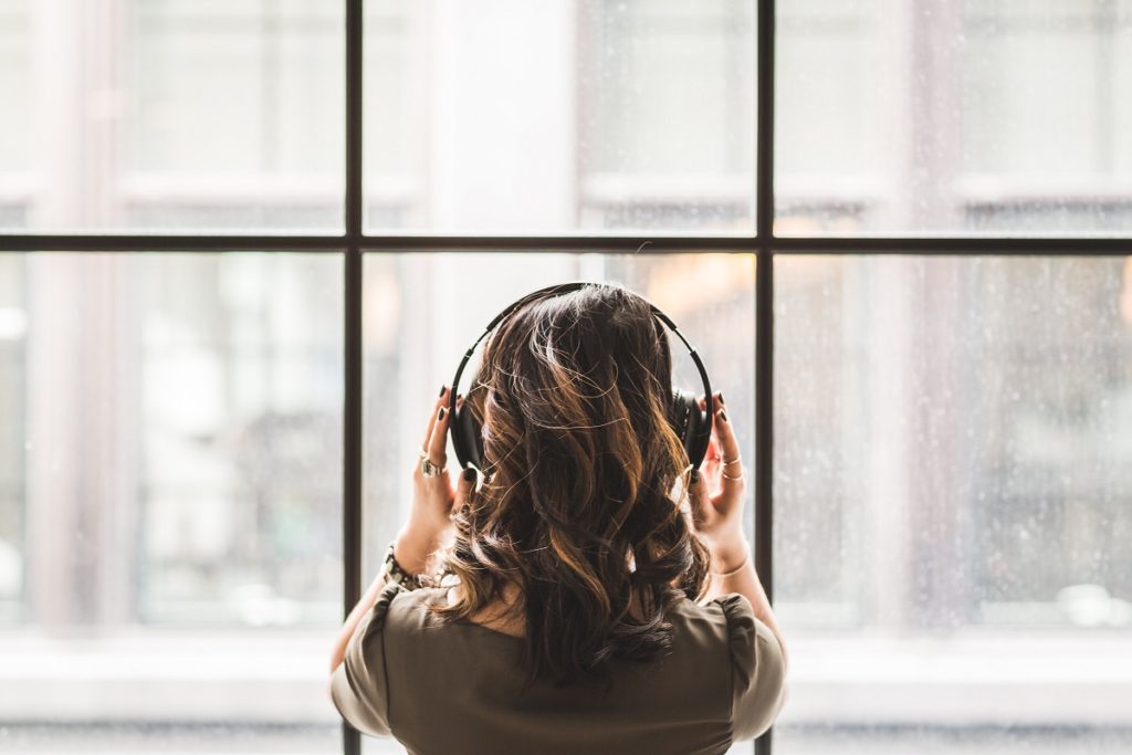 girl with headphones on looking out the window