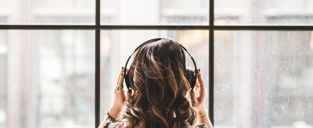 girl with headphones on looking out the window