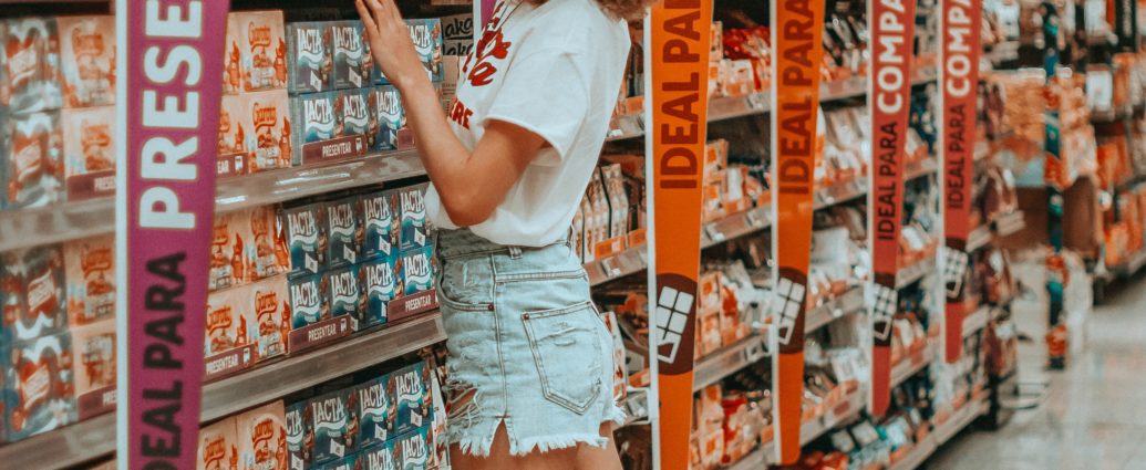 Girl reaching for food product on supermarket shelf