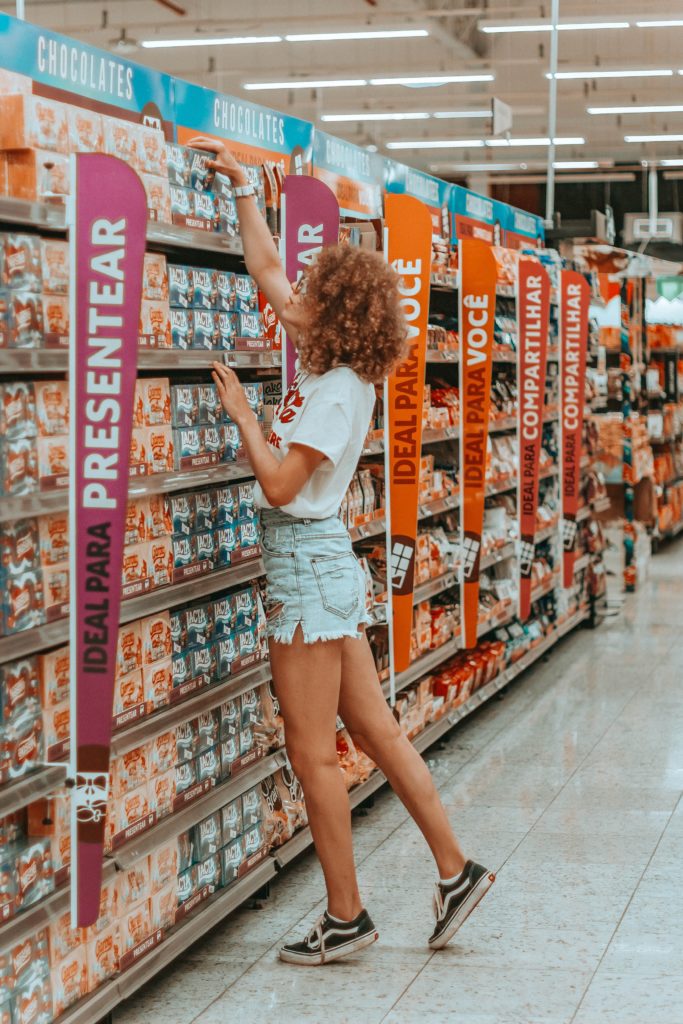 Girl reaching for food product on supermarket shelf