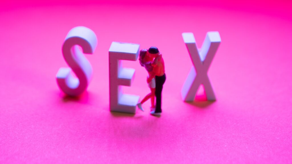 Pink background with the word 'sex' and two people kissing