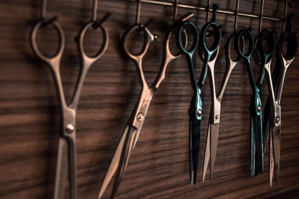 Row of hairdressing scissors hanging on a wooden wall