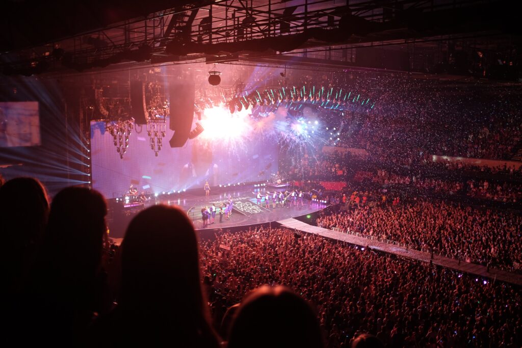 A photo from Taylor Swift's 1989 world tour. The stage lights are orange, blue and purple. Fans will be excited to see if she includes her track All Of The Girls You Loved Before on the setlist for her ongoing Eras tour.