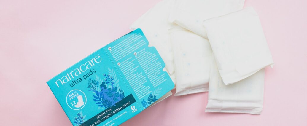 A box of period pads and some pads on a pink background