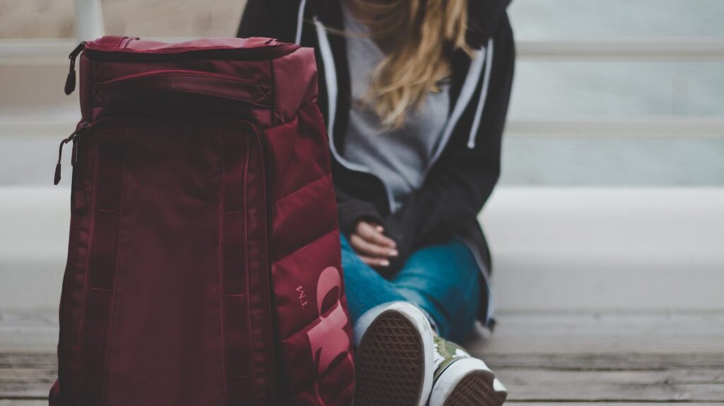 a woman sitting on the floor with her suitcase, about to embark on her Euro Summer trip.