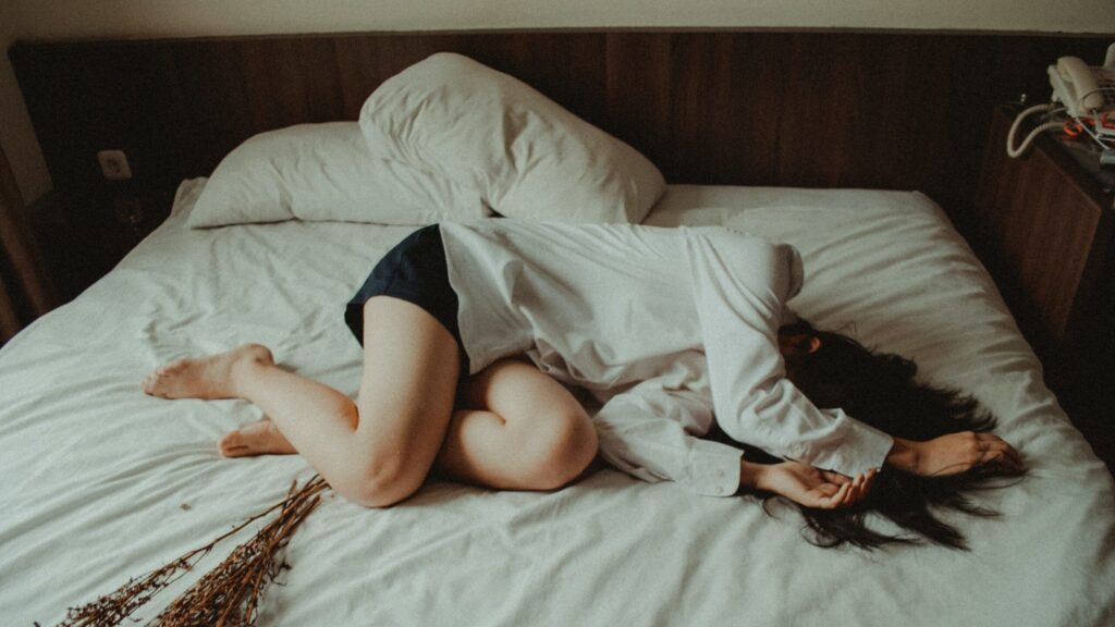 Woman lying on a bed, in distress.