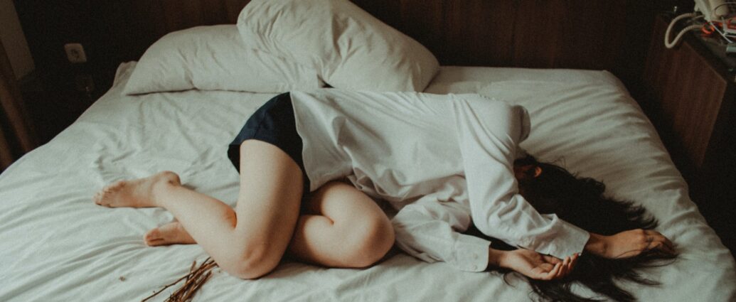 Woman lying on a bed, in distress.