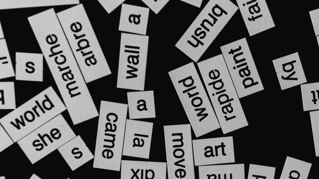 Image shows a black background with white stickers containing words in different languages