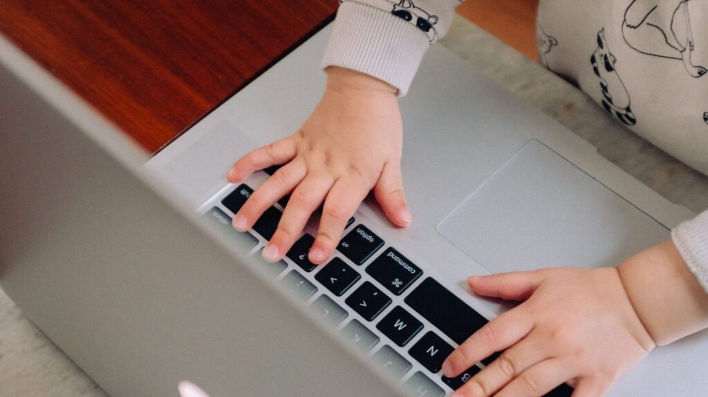 Child using a laptop to represent the way working mothers face disproportionate inequality in the workplace.