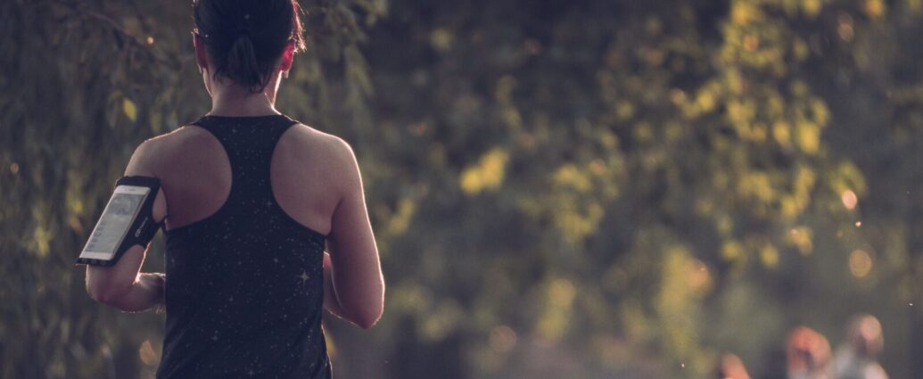 A woman running through a wooded area.