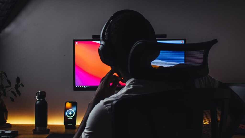 Person wears headphones in front of computer. There is a clapperboard pictured left, a common tool for YouTubers like Ballinger