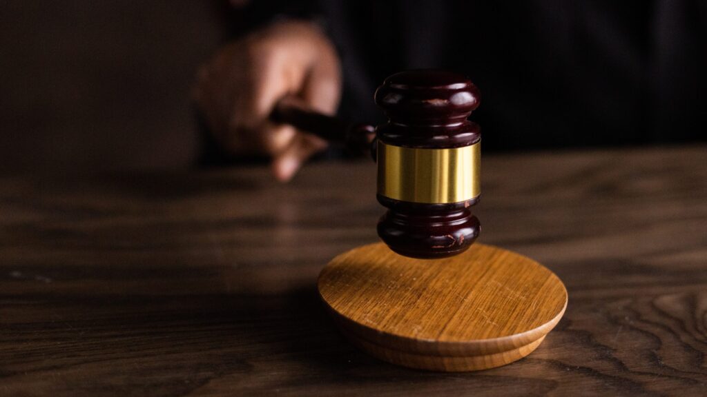 A wooden gavel is struck against a sound block.