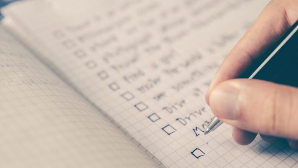 Image shows a person writing a daily habits to-do list in a notepad