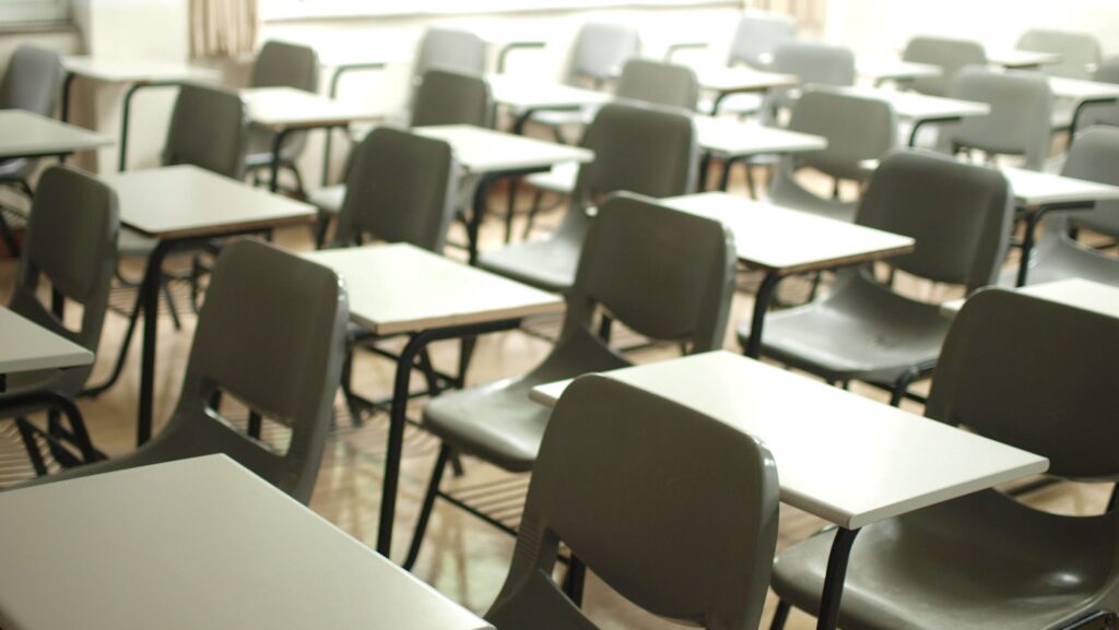 Image of chairs and desks lined up in a school hall.