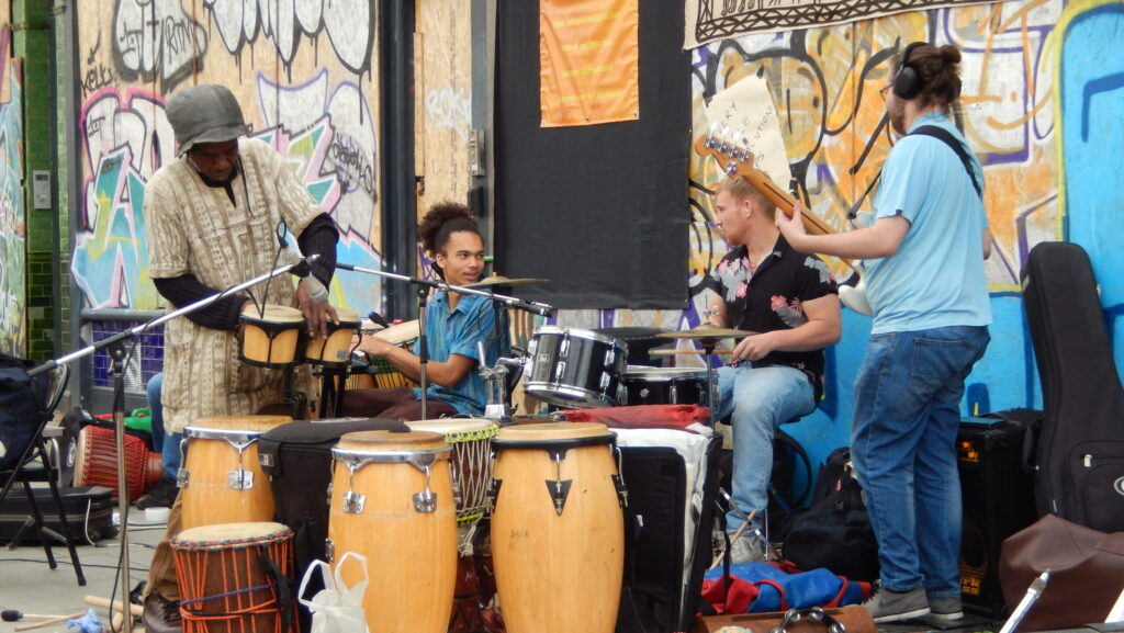 Four musicians surrounded by drums in preparation for a performance at Notting Hill Carnival.