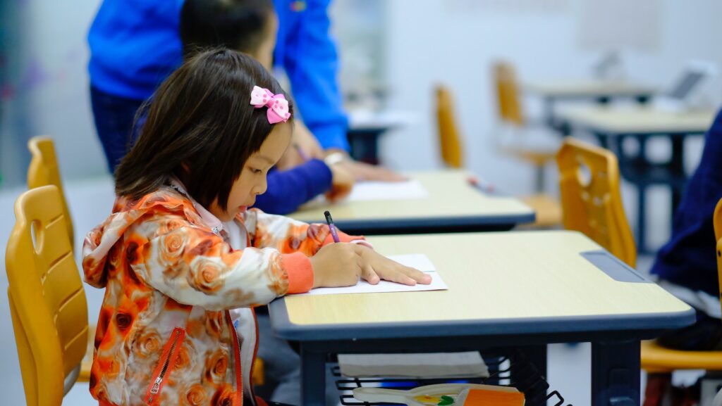 Little girl sitting at a school desk and writing.