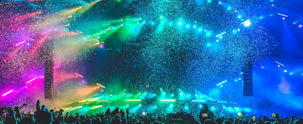 pink, green, and blue lights illuminating a concert stage.