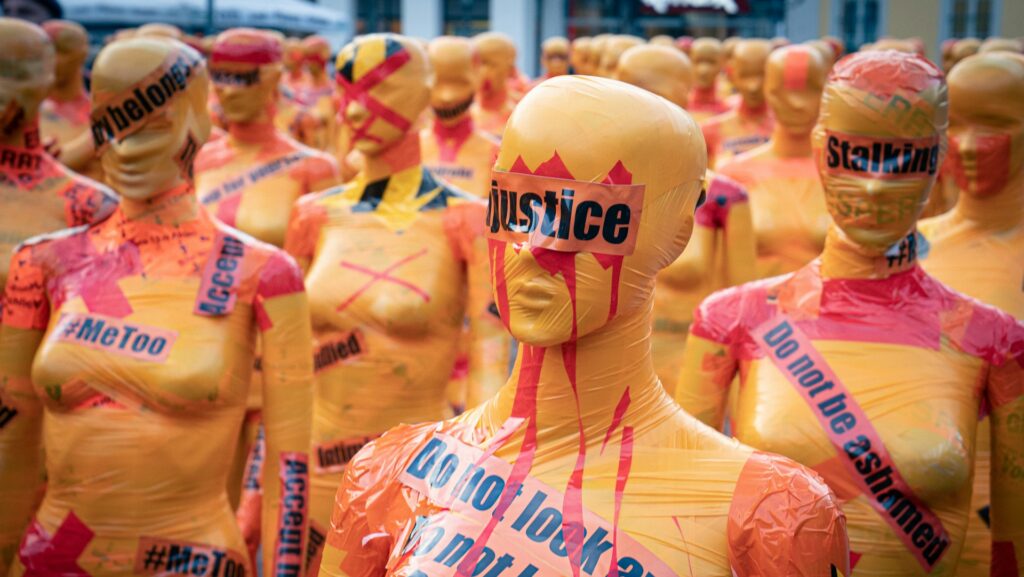 Yellow female status with red paint on them and black text reading 'justice'