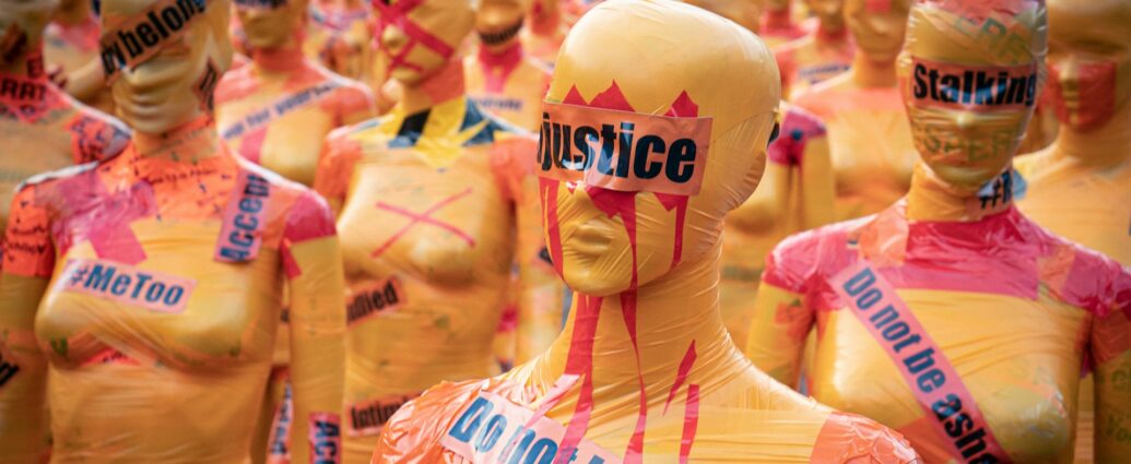 Yellow female status with red paint on them and black text reading 'justice'