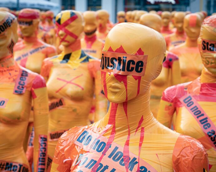 Yellow female status with red paint on them and black text reading 'justice'