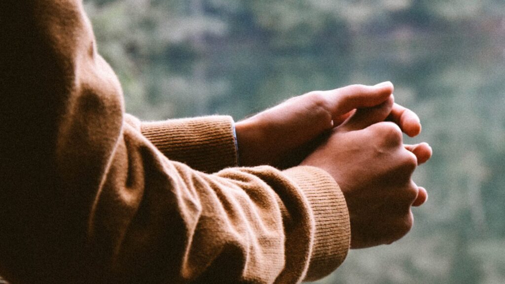 Someone resting their hands on railing looking out onto a lake