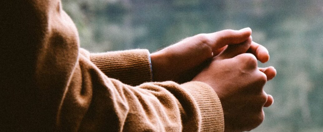 Someone resting their hands on railing looking out onto a lake