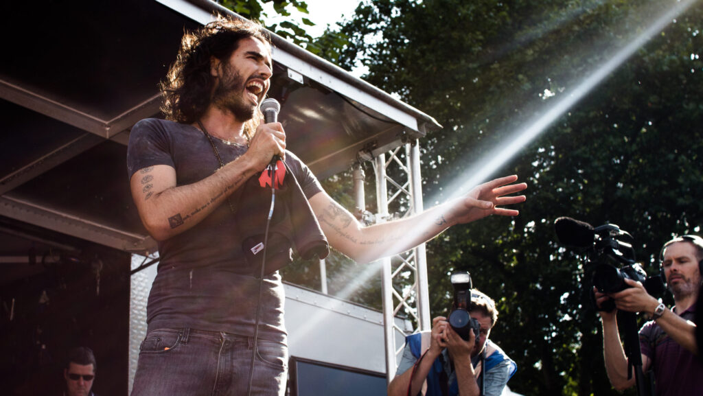 An image of Russell Brand speaking at an event.