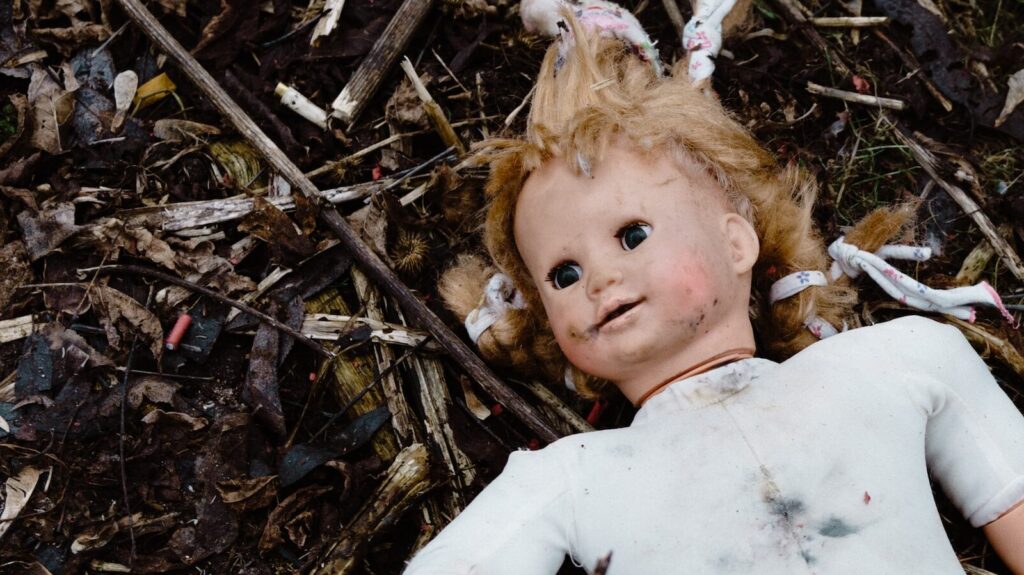 Image shows a tarnished Baby Annabel doll lying in the dirst.