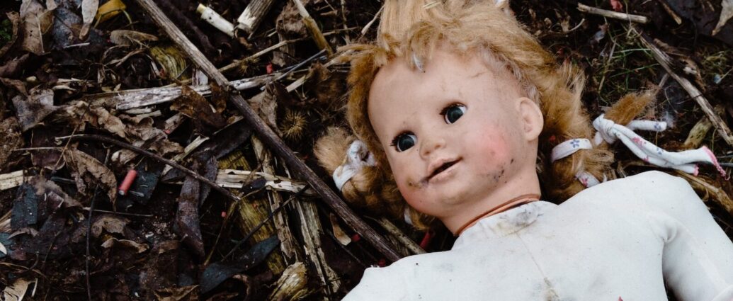 Image shows a tarnished Baby Annabel doll lying in the dirst.