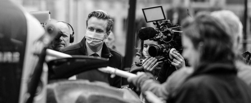 Black and white image of journalists reporting at the scene.