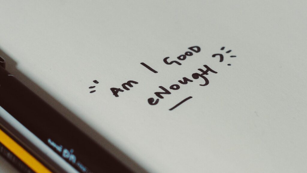 Image shows a piece of paper with the words 'Am I good enough?' on it [self-optimisation]