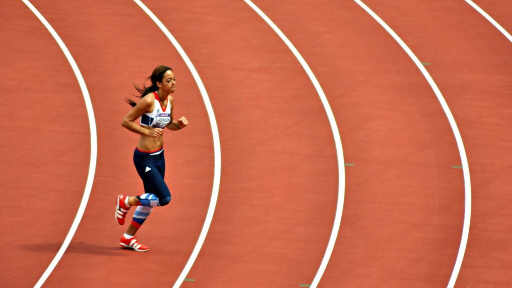 Image shows athlete Katarina Johnson-Thompson running across a track.