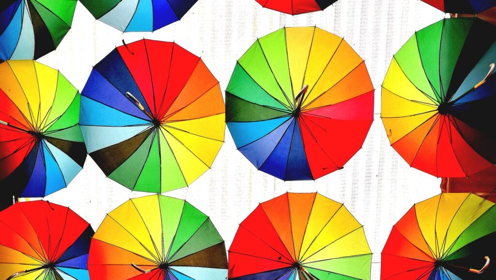 Image shows various umbrellas of different colors hanging horizontally