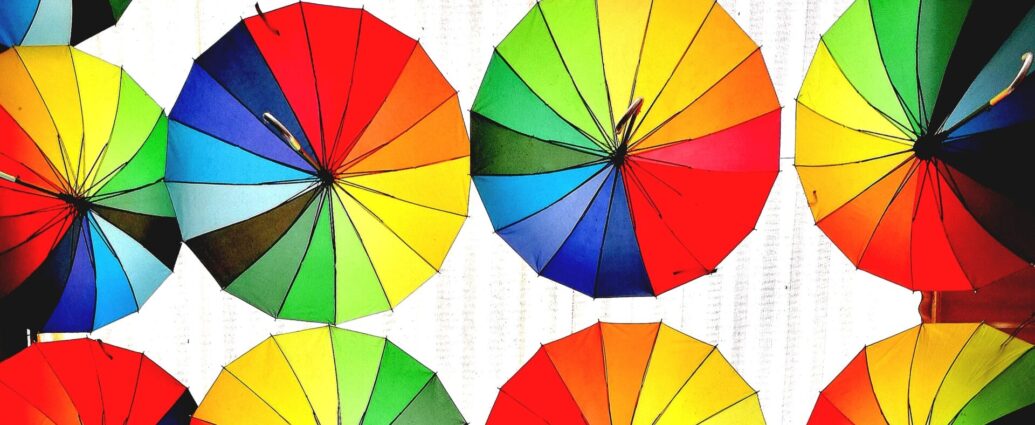 Image shows various umbrellas of different colors hanging horizontally