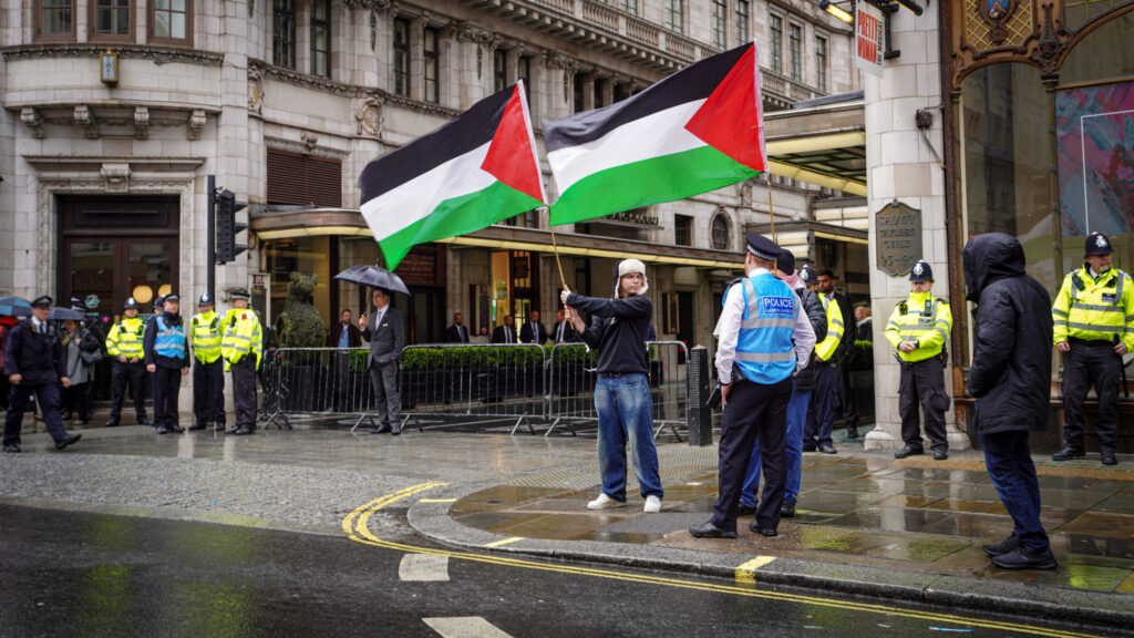 Two activists raise Palestinian flags in front of London's Savoy Hotel.