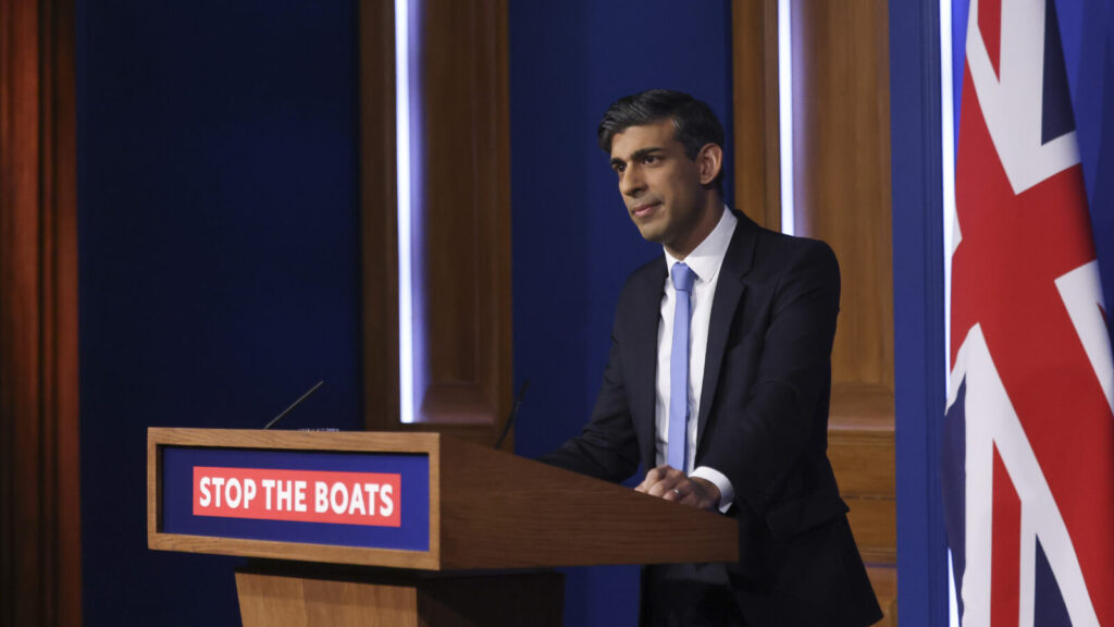 UK Prime Minister Rishi Sunak behind a podium that says 'stop the boats'