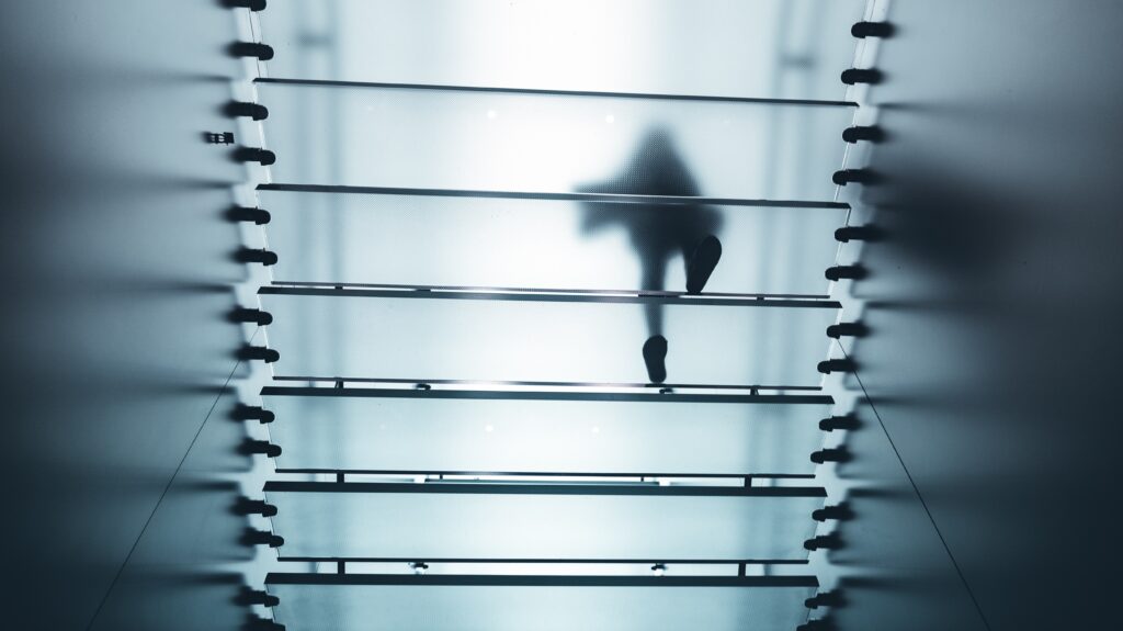 A figure walking above frosted glass stairs