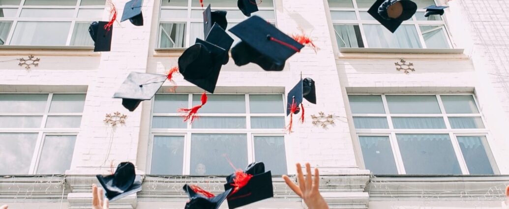 Image shows a group of graduates throwing their caps into the air [after graduating]