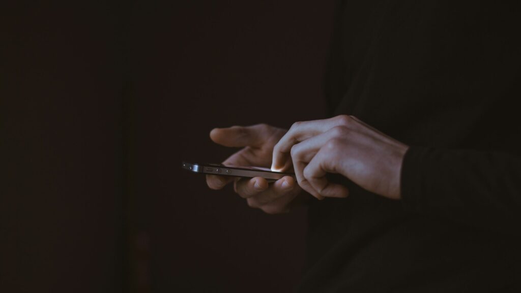 Silhouette of person holding phone with illuminated screen.