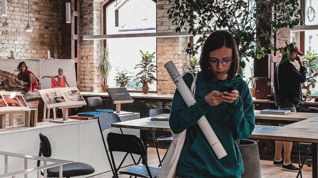 Image shows a young woman on her phone in an office space [Gen Z]