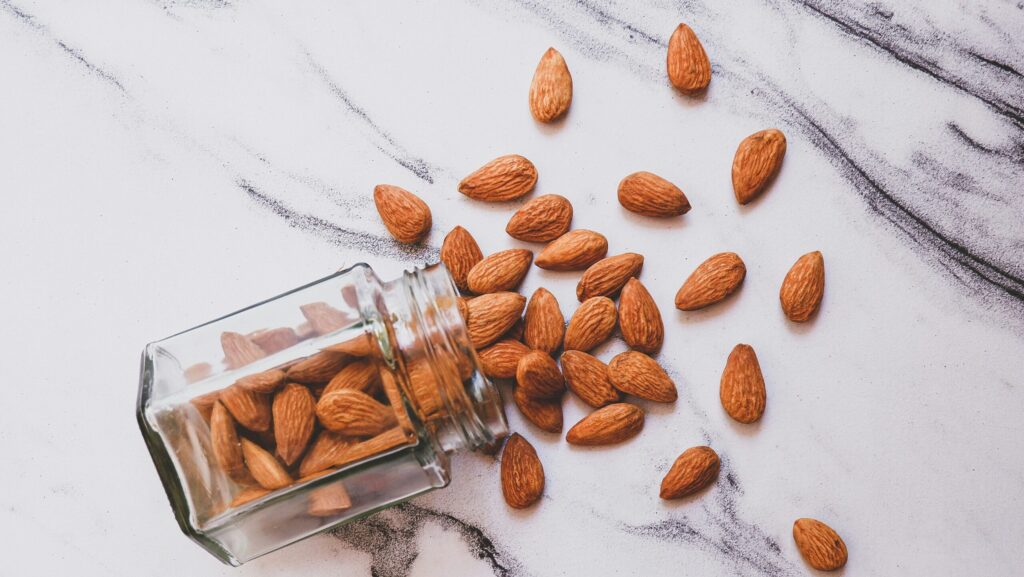 Brown almonds on white marble surface.