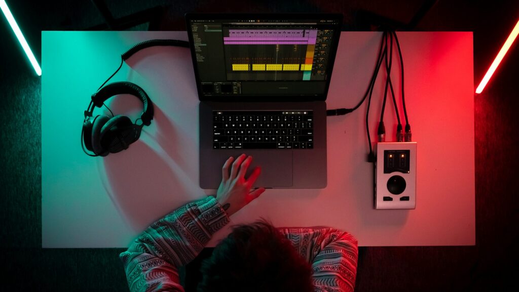 A person sitting in front of a desk with a laptop and headphones working on media leaks