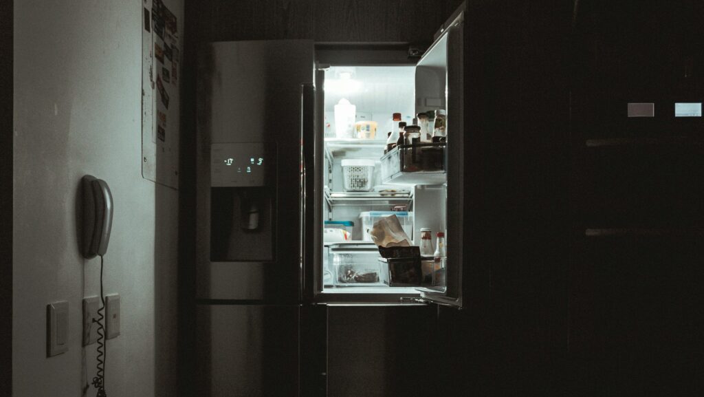 An open fridge shining light in a dark room.