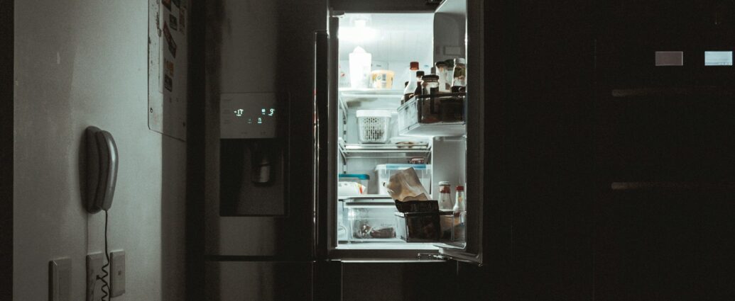 An open fridge shining light in a dark room.