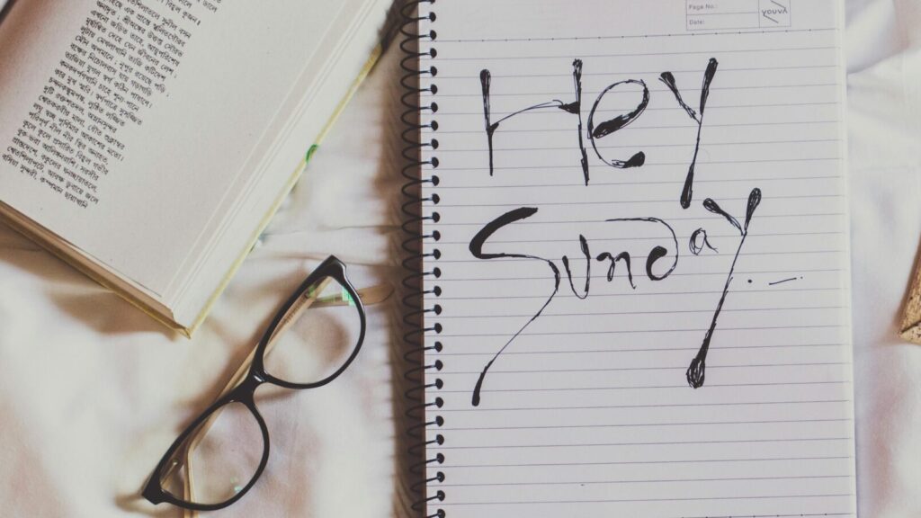 A notepad with writing saying 'Happy Sunday' next to a pair of glasses. Sunday Reset