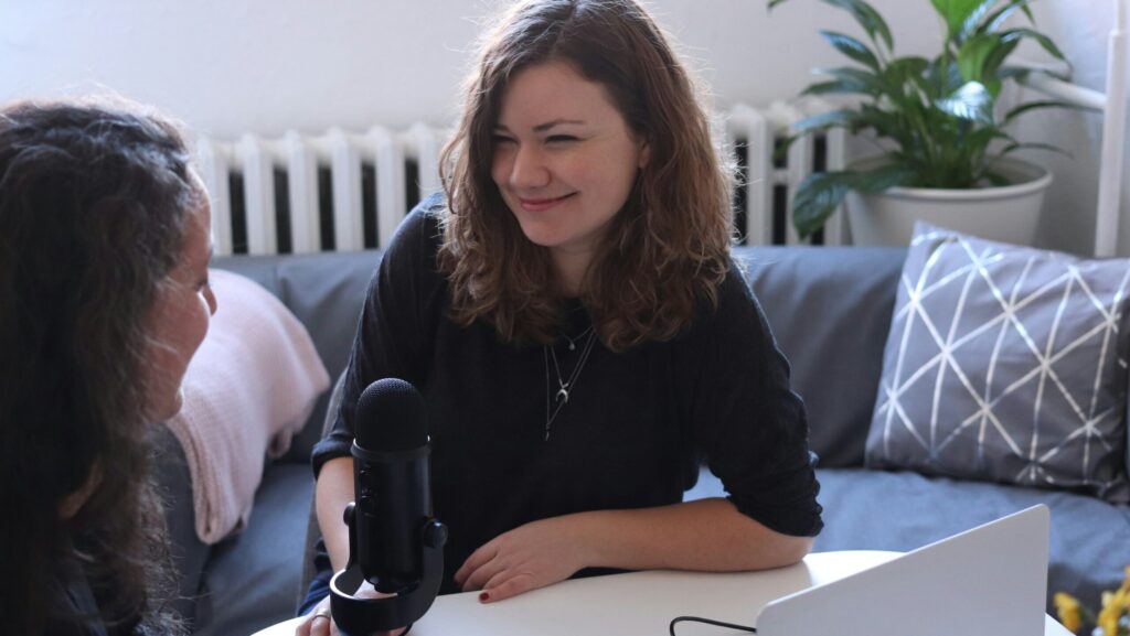 Journalist with a microphone smiles to an interviewee.