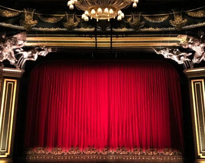 Image shows a closed red curtain on theatre stage - is the stage set for musical after musical?